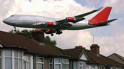 A plane flying close to houses.